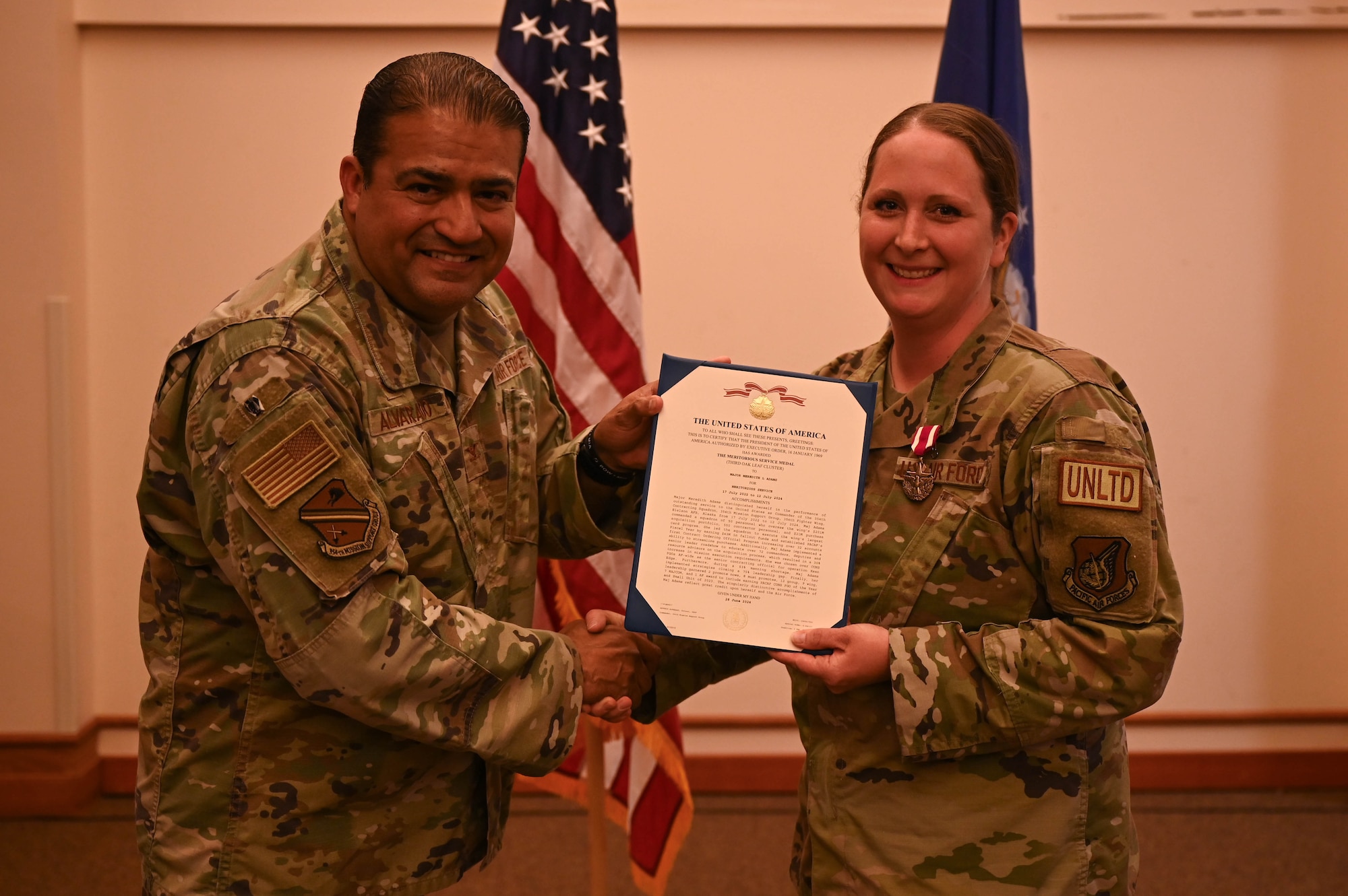 Col. Antonio Alvarado hands the Meritorious Service Medal certificate to Maj. Meredith Adams.