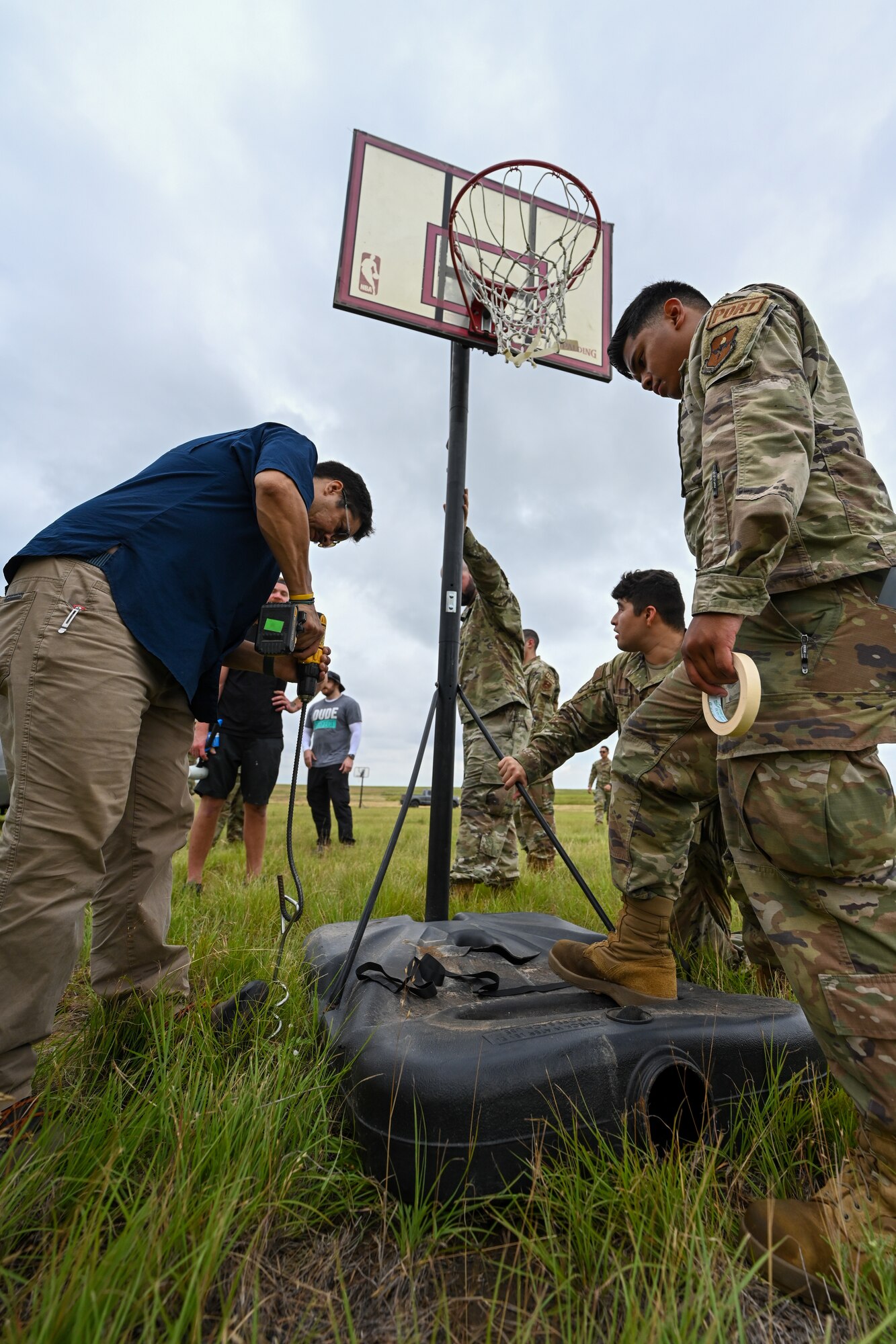 Airmen from the 97th Air Mobility Wing help the Dude Perfect film crew set up at Sooner Drop Zone, Oklahoma, June 11, 2024. In total, 47 basketball hoops were arranged on the drop zone in hopes of catching one of 1,000 basketballs dropped from a C-17 Globemaster III aircraft. (U.S. Air Force photo by Airman Lauren Torres)