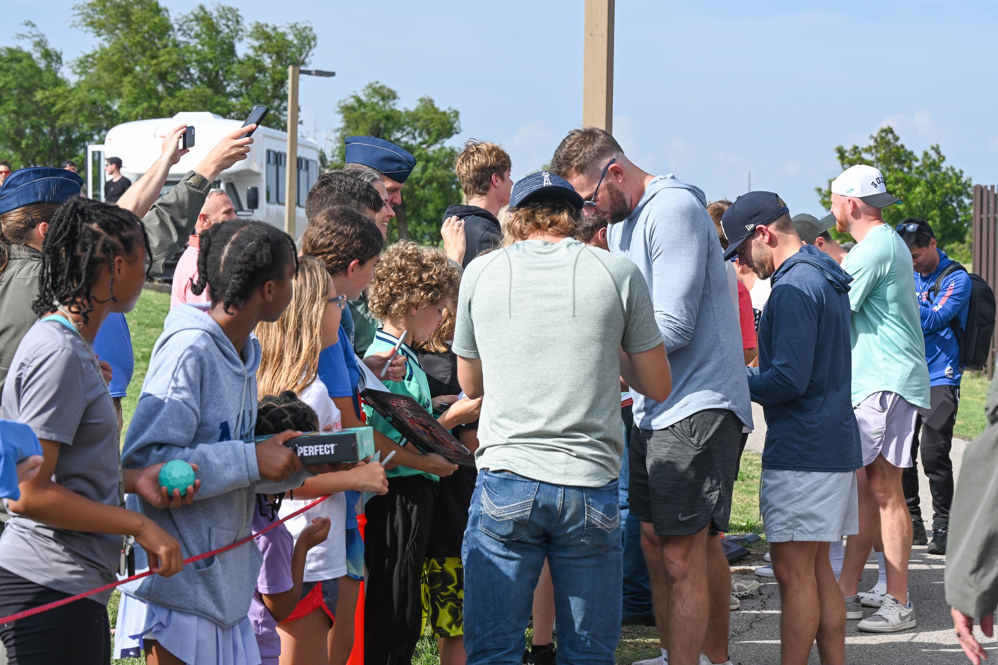 The cast of Dude Perfect sign autographs and take photos with Airmen and families at Altus Air Force Base (AFB), Oklahoma, June 11, 2024. The Dudes took time to meet and greet Airmen and families during their visit to Altus AFB before they performed multiple stunts for their video featuring the 97th Air Mobility Wing. (U.S. Air Force photo by Senior Airman Trenton Jancze)