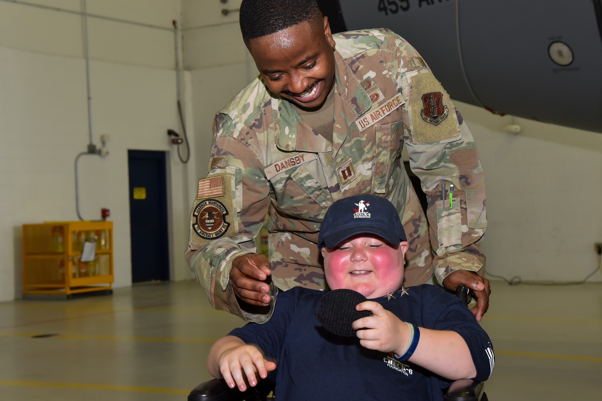 An Airmen giving a child in a wheelchair a military patch.