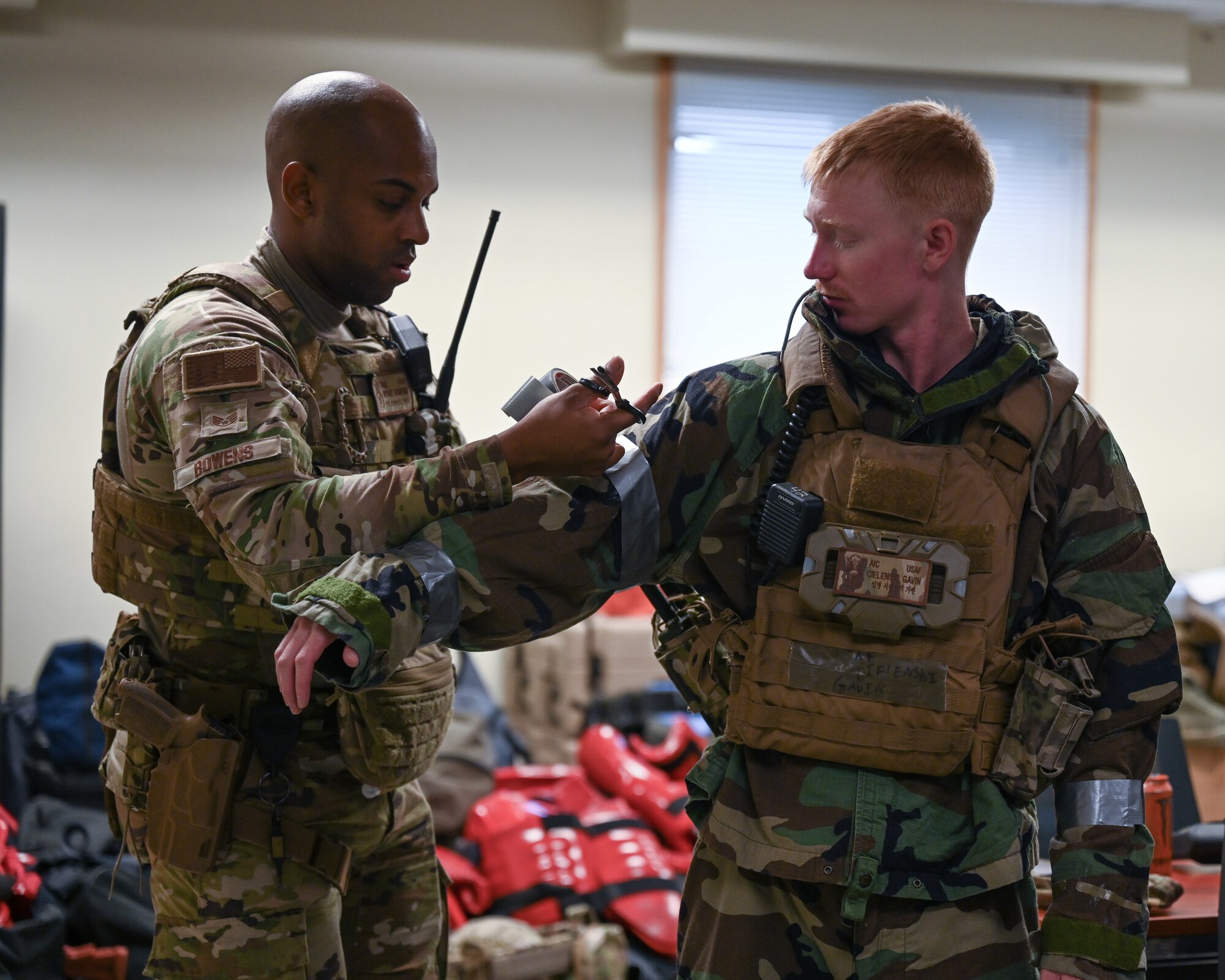 U.S. Air Force Staff Sgt. Bryant Bowens, left, 8th Security Forces Squadron flight sergeant, assists Airman 1st Class Gavin Cielenski, 8th SFS installation entry controller, in donning chemical, biological radioactive, nuclear gear for a CBRN-driving training during exercise Beverly Sentinel 24-2 at Kunsan Air Base, Republic of Korea