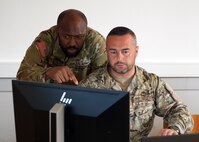 Maryland Army National Guard Sgt. Emmanuel Unaka, cyber threat intelligence analyst with Cyber Protection Team 169, listens to Armed Forces of Bosnia and Herzegovina Lt. Armin Kolašinac, a Security Operations Center member, during the Adriatic Regional Security Cyber Cooperation exercise at the Slovenian Armed Forces Baron Andrej Čehovin barracks in Postojna, Slovenia, July 5, 2024. The two-week cybersecurity training event included 60 representatives from Albania, Bosnia and Herzegovina, Croatia, Kosovo, Montenegro, Slovenia and North Macedonia and their National Guard State Partnership Program counterparts from New Jersey, Maryland, Minnesota, Iowa, Maine and Colorado, respectively.