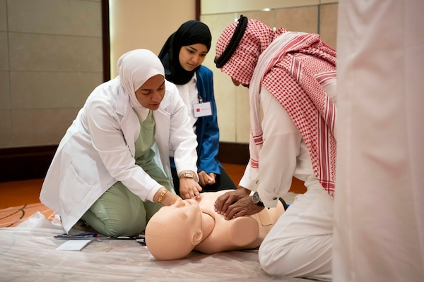Participants from the Multinational Combat Casualty Care Engagement conference, exchange techniques and best practices during a simulated cardiopulmonary resuscitation training, July 2.