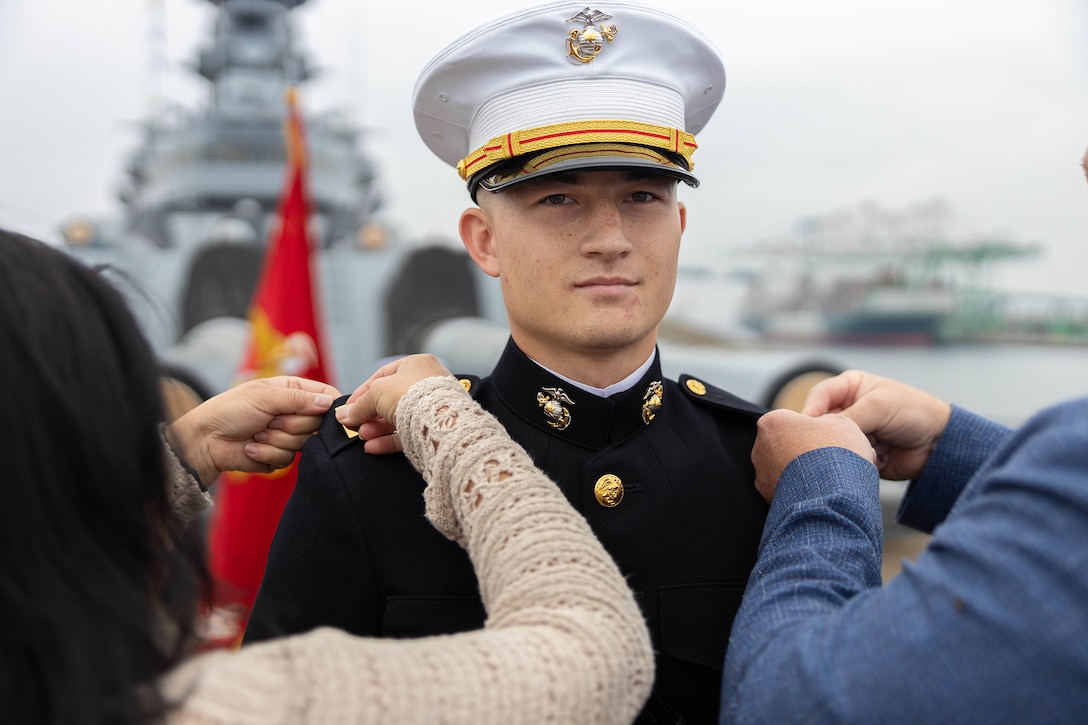 Close-up of a uniformed service member being pinned by two people during a ceremony.