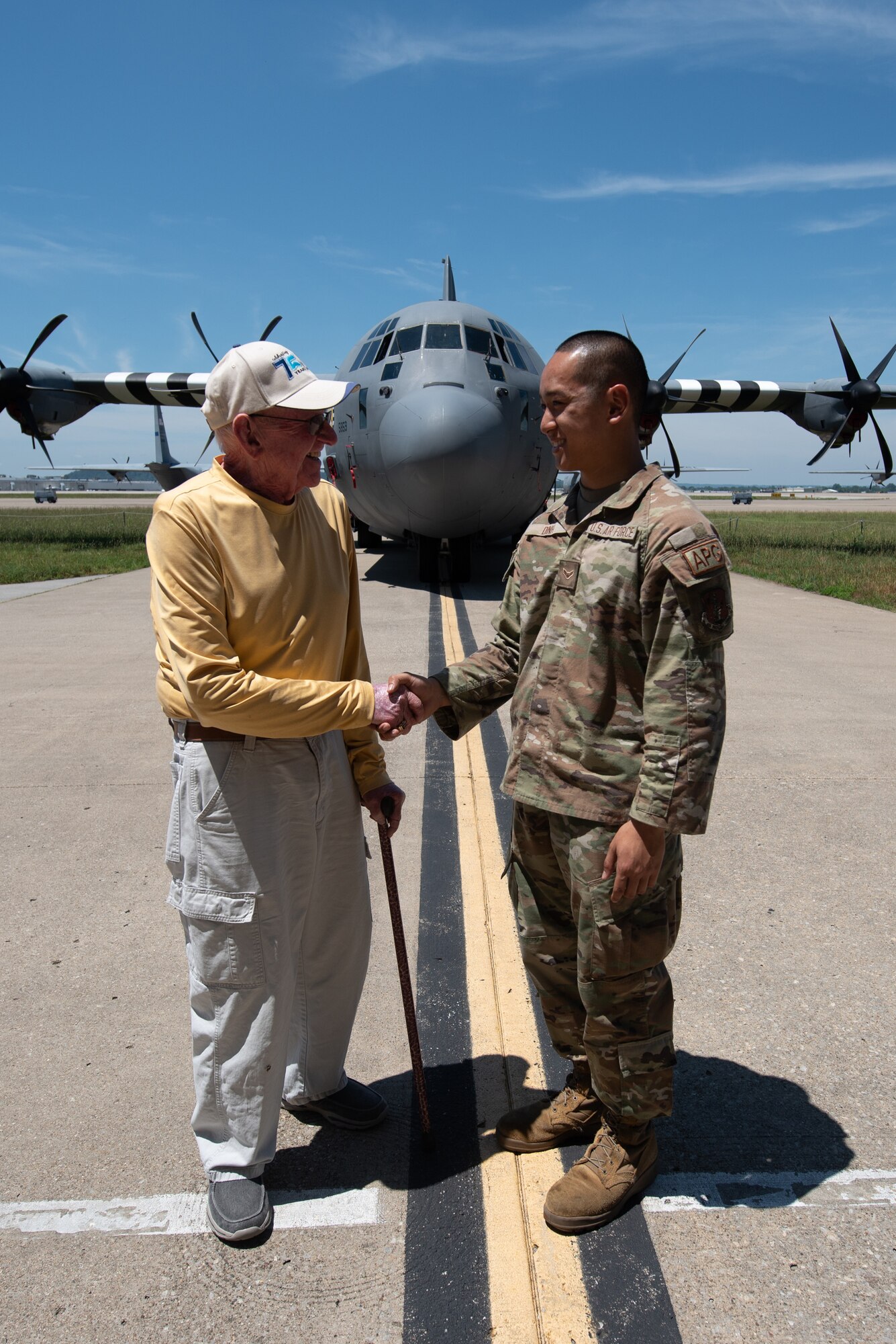 Retired Senior Master Sgt. Marshall Leigh, left, a former non-destructive inspection and aircraft structural maintainer for the Kentucky Air National Guard, and Airman 1st Class Ryan Dinh, a crew chief assigned to the 123rd Aircraft Maintenance Squadron, shake hands in the front of a 123rd Airlift Wing C-130J Super Hercules aircraft at the Kentucky Air National Guard Base in Louisville, Ky., June 28, 2024. At 87, Leigh was the oldest Airman to attend a cookout for current and former members of the unit, and Dinh was the youngest at 19. (U.S. Air National Guard photo by Phil Speck)