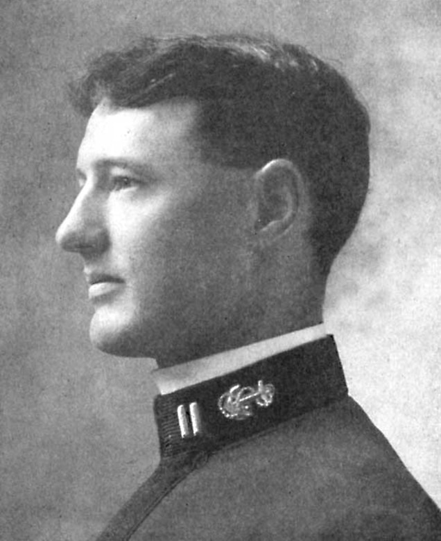 A profile view of a man in a Navy uniform posing for a photo.