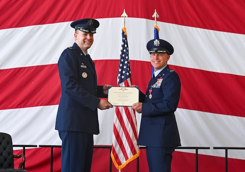 Man in uniform passes award to another man in uniform.