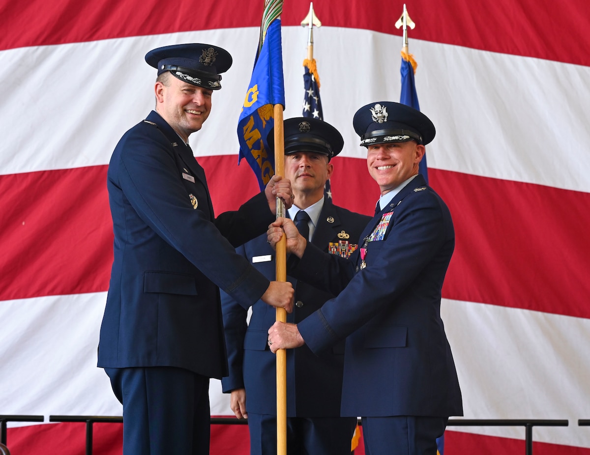 People in uniform passing a guidon.