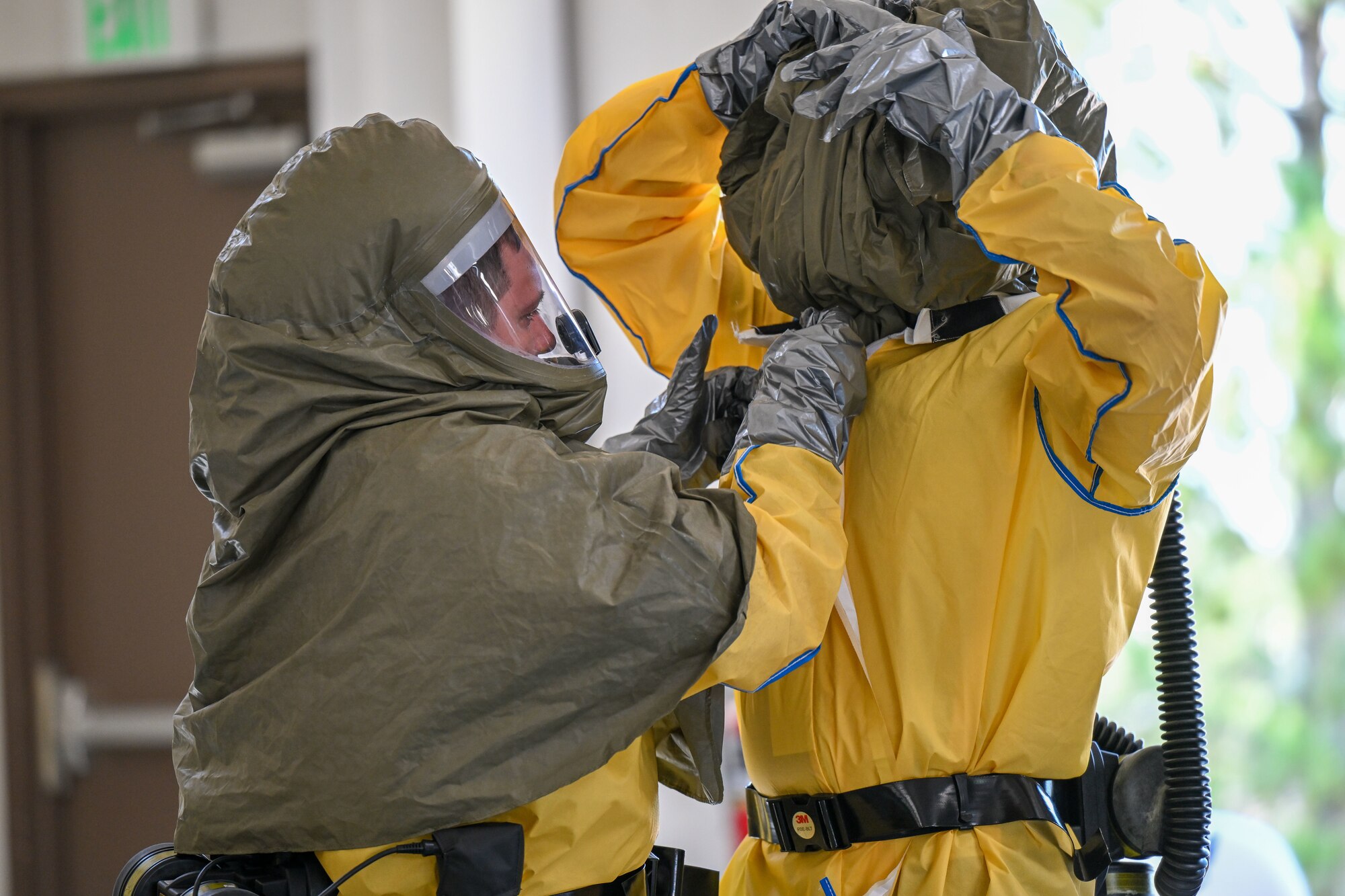 Two people assisting one another with protective chemical gear