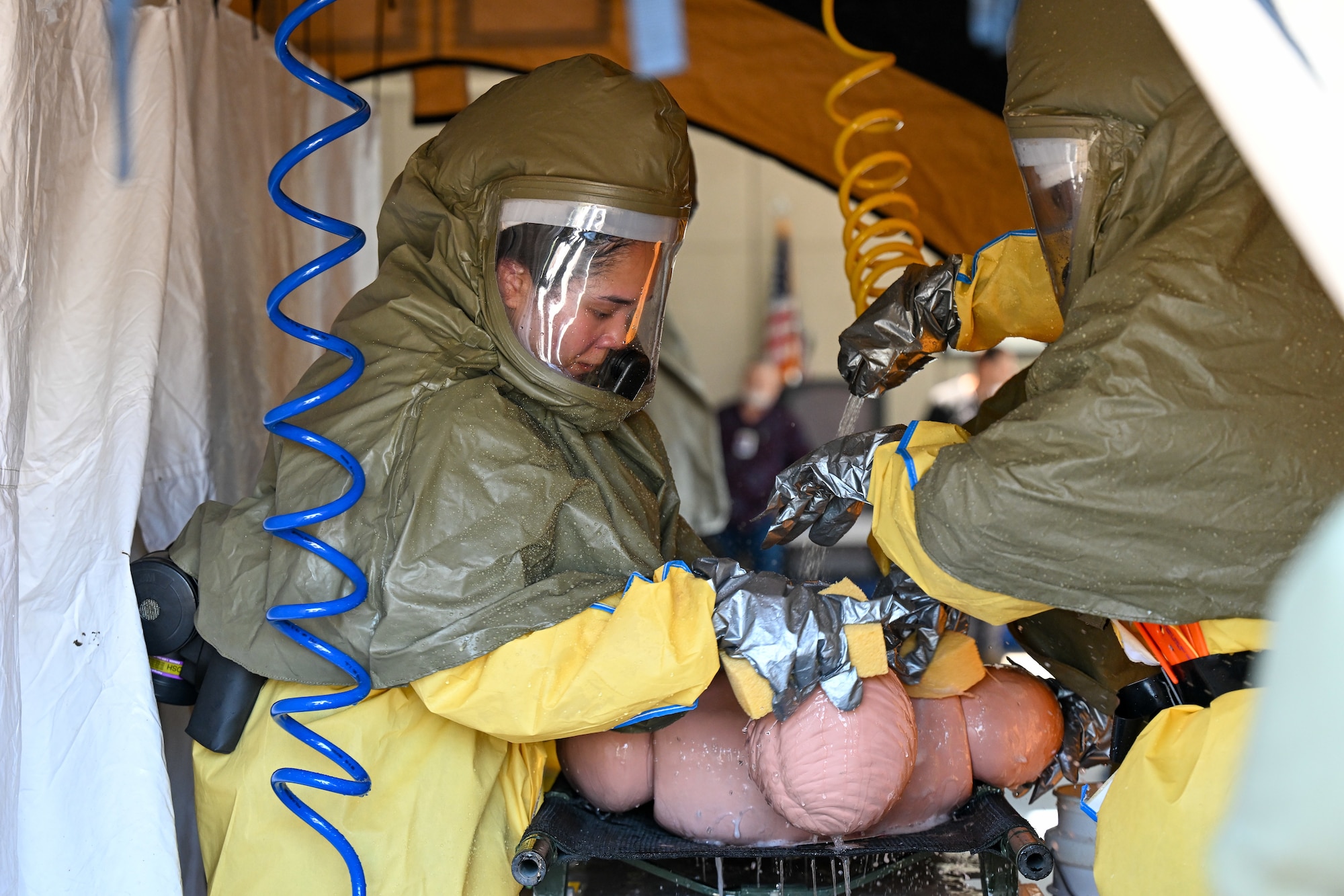 Two people work to decontaminate a training dummy