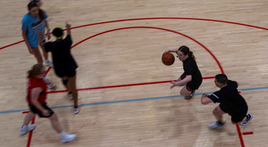 U.S. Air Force Airman 1st Class Madison Snyder, 5th Operational Medical Readiness Squadron public health technician and Lady Bomber (center), plays basketball at Minot Air Force Base, North Dakota, July 10, 2024. Snyder’s favorite parts about basketball include the energy, competitiveness and scoring. (U.S. Air Force photo by Airman 1st Class Alyssa Bankston)