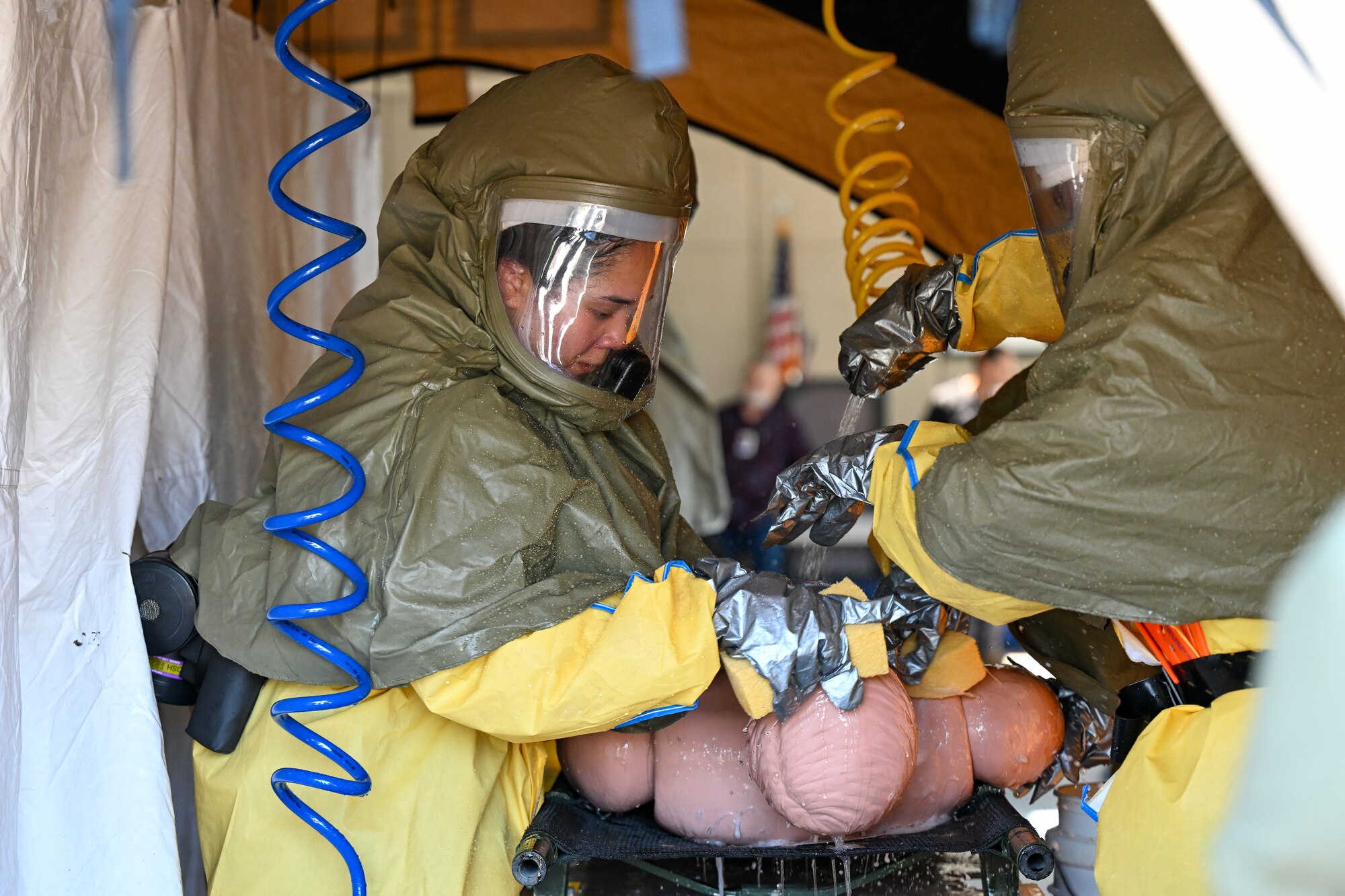 Two people work to decontaminate a training dummy