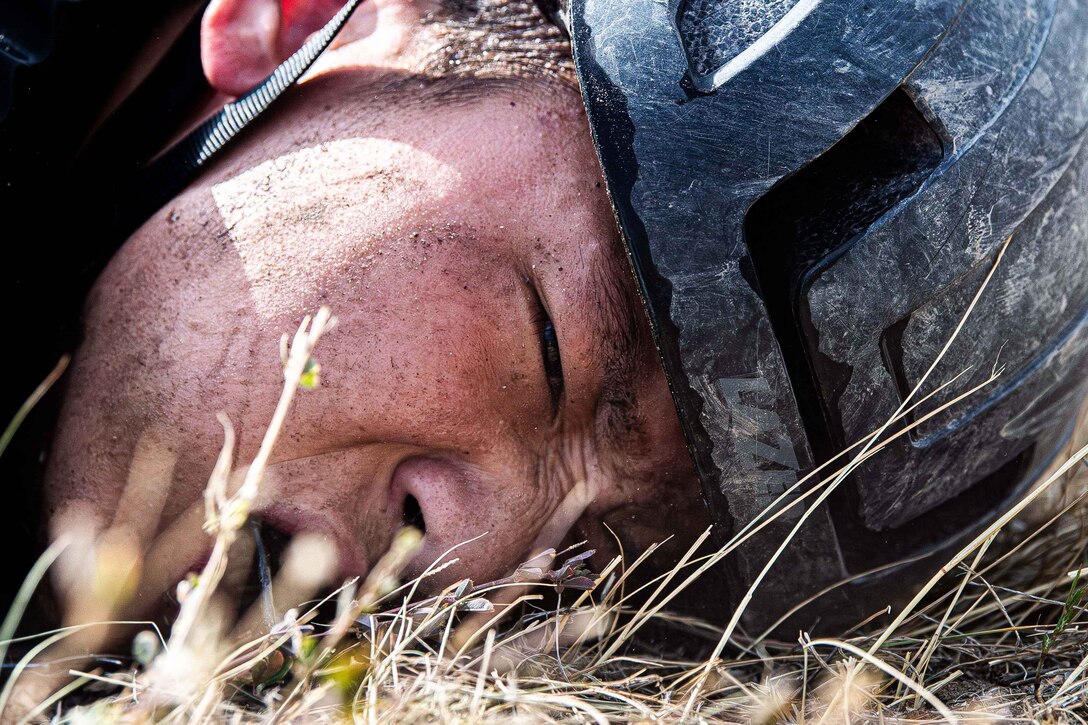 An Air Force cadet grimaces while lying on the ground.