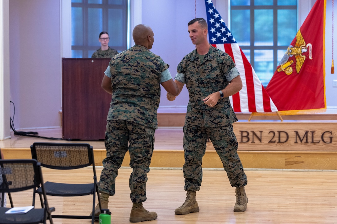 U.S. Marine Corps 1st Sgt. Gary Moll, right, outgoing senior enlisted leader, Headquarters and Service Battalion, 2nd Marine Logistics Group, shakes hands with Sgt. Maj. Devon Fischer, left, incoming sergeant major, H&S Battalion, 2nd MLG, during the relief and appointment ceremony on Camp Lejeune, North Carolina, July 10, 2024. The historic post and relief ceremony is a time-honored tradition within the U.S. Marine Corps, allowing the new appointed Sergeant Major the opportunity to introduce himself to the Marines now under his charge. (U.S. Marine Corps photo by Lance Cpl. Jessica J. Mazzamuto)