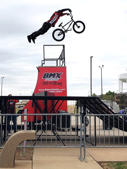 rider hangs on to handlebars of a BMX bike while about 10 feet above a ramp.