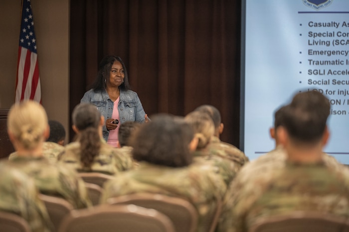 A woman speaks to uniformed service members during a briefing.