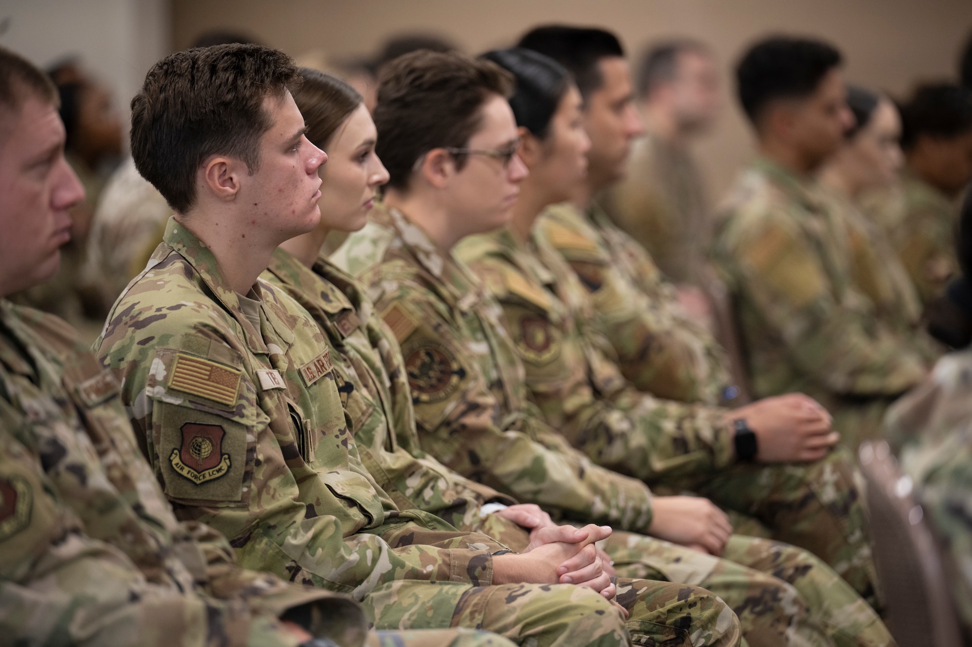 uniformed service members sit in a briefing.