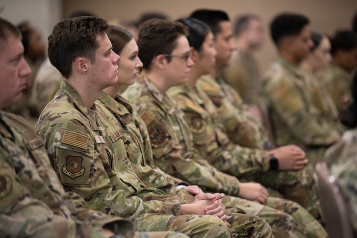 uniformed service members sit in a briefing.