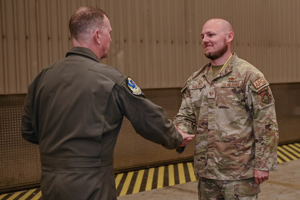 Gen. Guillot hands a coin to an Airmen in the 18th Fighter Generation Squadron inside an F-16 hangar.