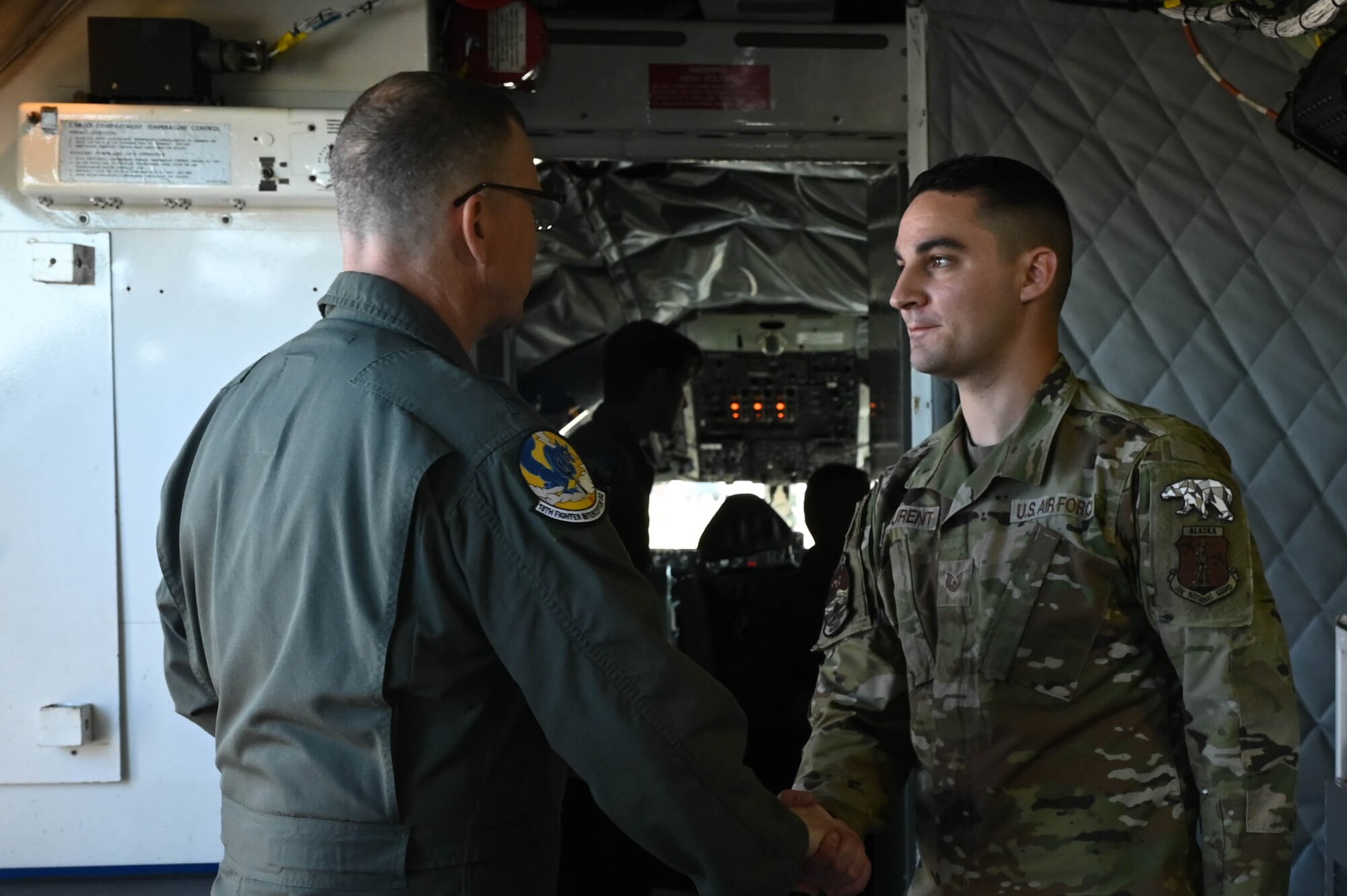 Gen. Guillot hands coin to an Airman from the 168th Wing in the inside of a KC-135 tanker.