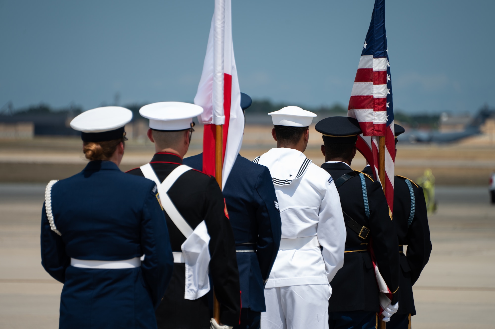 Six service members from all different military branches stand outside holding the American flag and Japan flag.