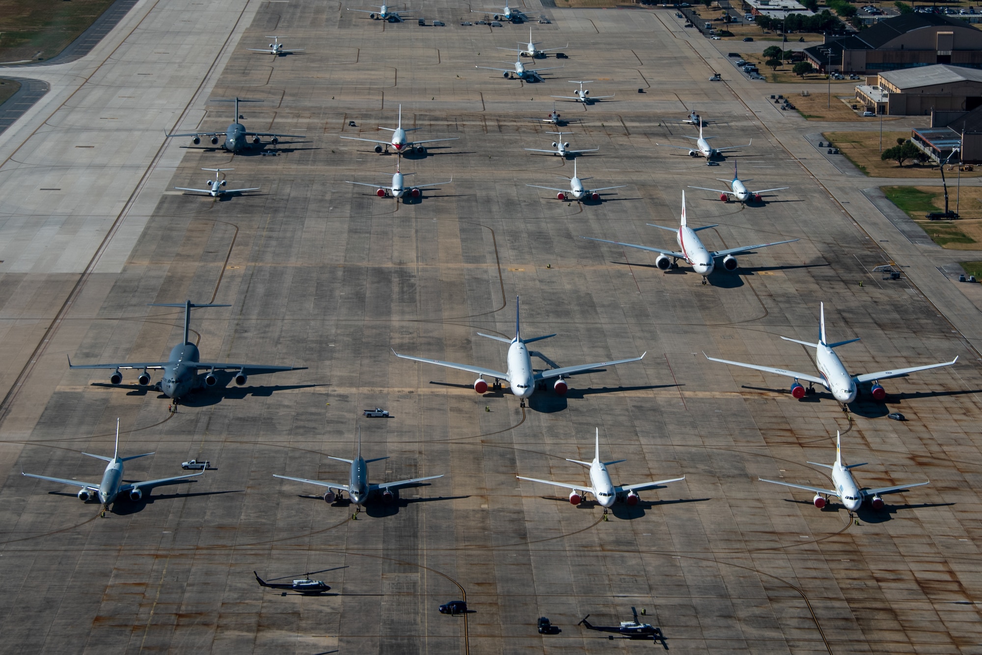 Several different types of aircraft all sit together outside on a flightline