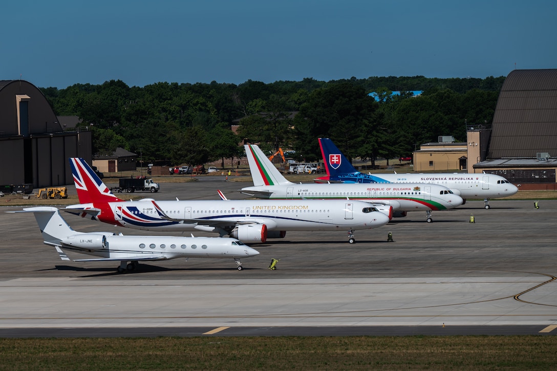 Four planes sit in a row outside on a flightline.