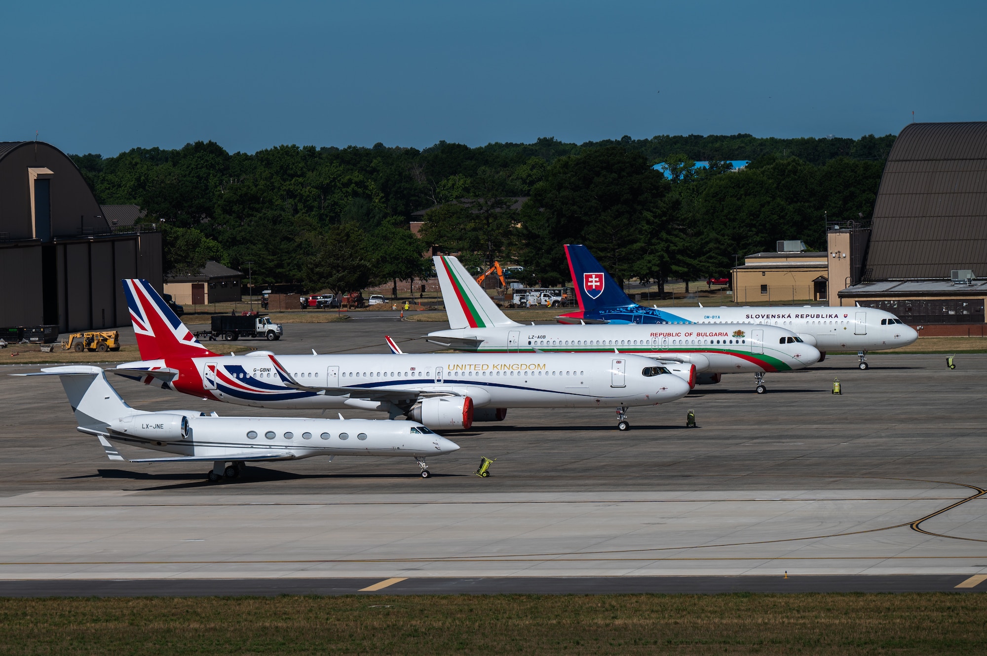 Four planes sit in a row outside on a flightline.