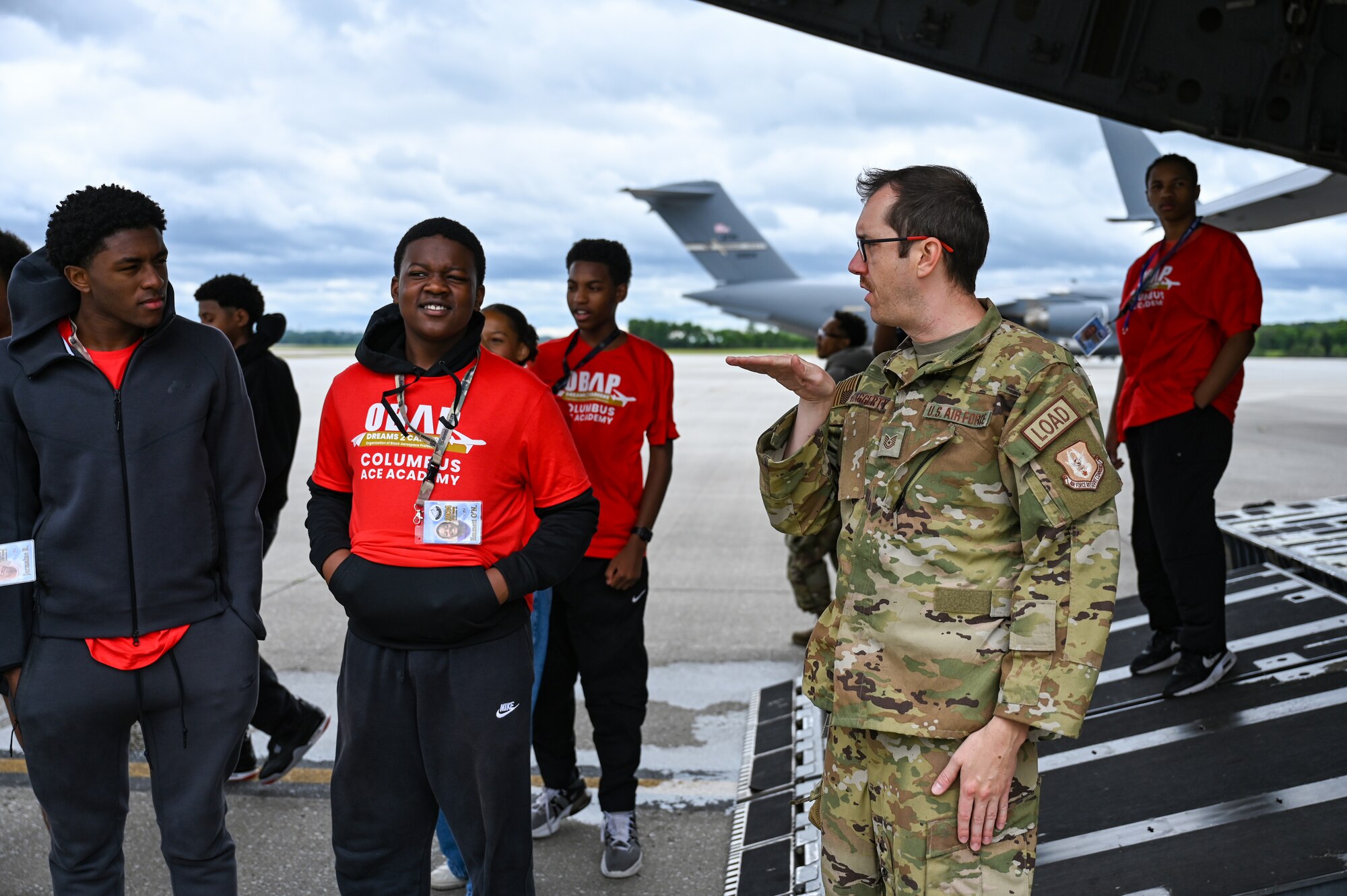 Tech. Sgt. Shawn Haggerty, 89th Airlift Squadron loadmaster, talks about the flying capabilities of a C-17 Globemaster III to young members of Buckeye Tigers as they watch a C-17 perform touch and goes on the flightline at Wright-Patterson Air Force Base, Ohio July 10, 2024. The Buckeye Tigers Aviation Program is an aviation organization focused on exposing young adults in middle and high school to various aviation careers in the Columbus and greater Central Ohio region.  Members get to experience actual flight in a real single engine airplane as the culminating event of OBAP’s (Organization of Black Aerospace Professionals) sponsored A.C.E. (Aviation Career Education) Academy. (U.S. Air Force photo by Mr. Patrick OReilly)