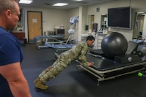 U.S. Air Force Airman 1st Class Nicholas Santos, 375th Medical Group physical therapy technician, Keesler Air Force Base, Mississippi, demonstrates an exercise to a patient at the 9th Medical Group physical therapy clinic at Beale Air Force Base, California, July 12, 2024.