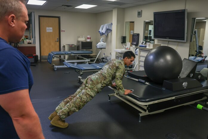 U.S. Air Force Airman 1st Class Nicholas Santos, 375th Medical Group physical therapy technician, Keesler Air Force Base, Mississippi, demonstrates an exercise to a patient at the 9th Medical Group physical therapy clinic at Beale Air Force Base, California, July 12, 2024.