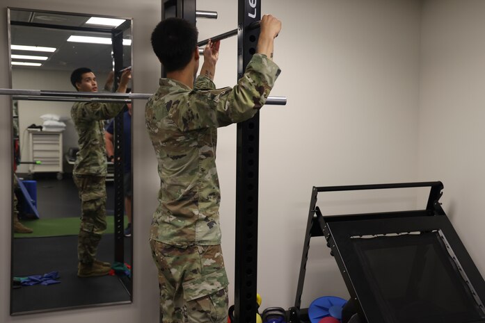 U.S. Air Force Airman 1st Class Nicholas Santos, 375th Medical Group physical therapy technician, Keesler Air Force Base, Mississippi, demonstrates an exercise to a patient at the 9th Medical Group physical therapy clinic, while in the Air Force Manning Assist Program at Beale Air Force Base, California, July 12, 2024.