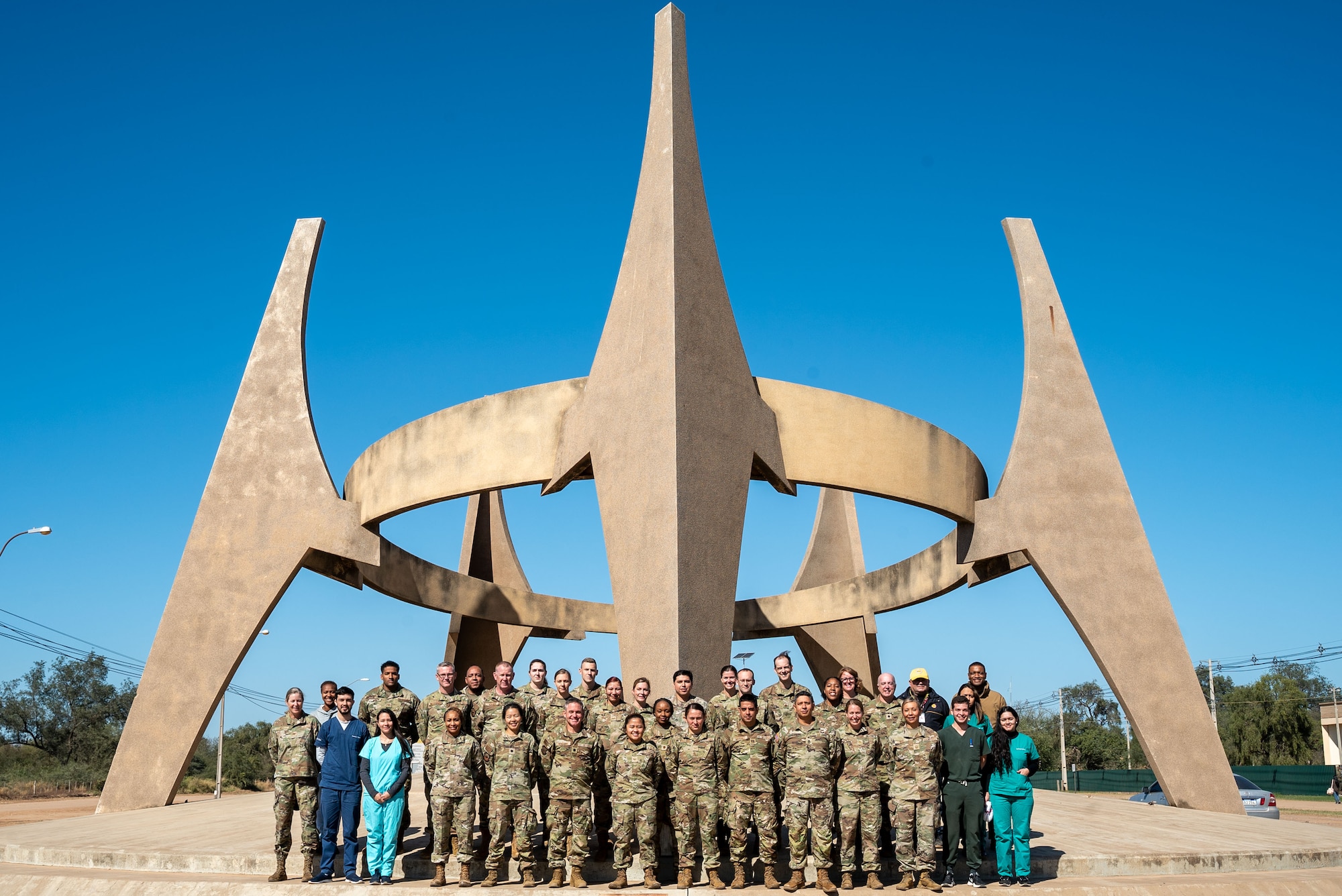 U.S. military members and Paraguyan medical students participating in AMISTAD 24 gather around the 75th anniversary monument of the founding of the Fernheim Colony in Filadelfia, Paraguay, July 16, 2024. AMISTAD brings U.S. military health professionals together with partner nation medical teams to train and learn best practices together. This 12th Air Force (Air Forces Southern) led mission delivers valuable experiences to U.S. and partner nation medical professionals while increasing their ability to quickly work together in emergency situations. (U.S. Air Force photo by Tech. Sgt. Carly Feliciano)