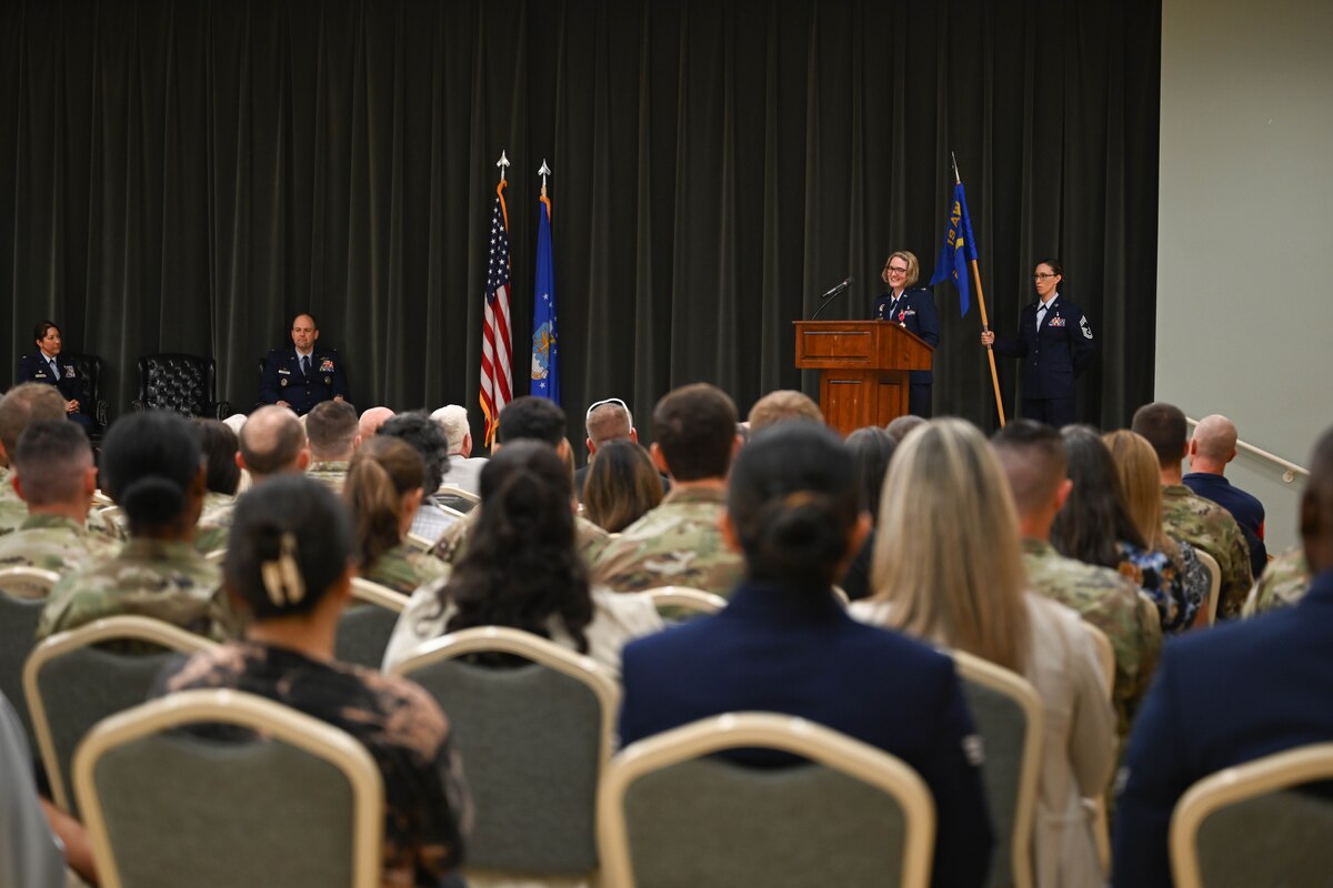 A crowd of people watch someone speak on stage.