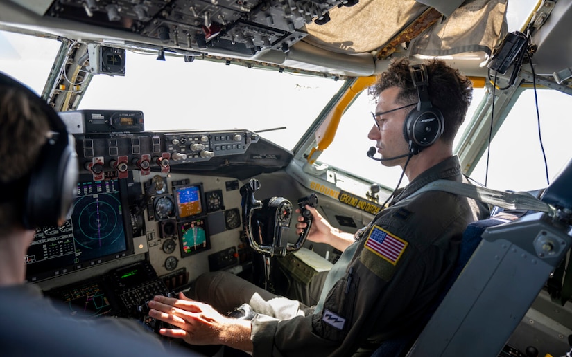 Two people sit in the cockpit of an airplane.