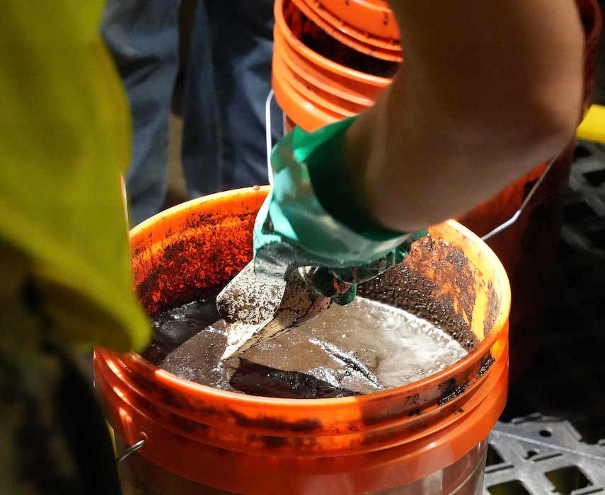 HALAWA, Hawaii (July 8, 2024) Cmdr. Richard Barkley, facilities operations officer, Navy Closure Task Force-Red Hill (NCTF-RH) collects a sample of sludge from fuel tank 7 at the Red Hill Bulk Fuel Storage Facility (RHBFSF) in Halawa, Hawaii, July 8, 2024.  About 12 gallons of sludge were removed from the tank. Sludge removal is part of the tank cleaning process for decommissioning the tanks. Charged with the safe decommissioning of the RHBFSF, NCTF-RH was established by the Department of the Navy as a commitment to the community and the environment. (U.S. Navy photo by Mass Communication Specialist 1st Class Glenn Slaughter)