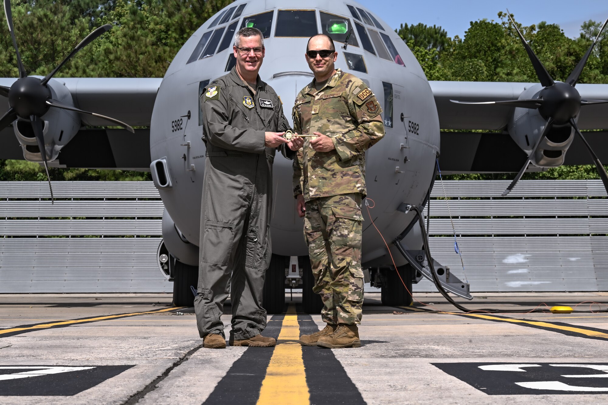 Master Sgt. Thaddeus Root, 910th Maintenance Group dedicated crew chief, receives the ceremonial key to the new C-130J-30 Super Hercules from Col. Michael Maloney, 910th Airlift Wing commander, at the Lockheed Martin production facility, Marietta, Georgia, July 16, 2024.