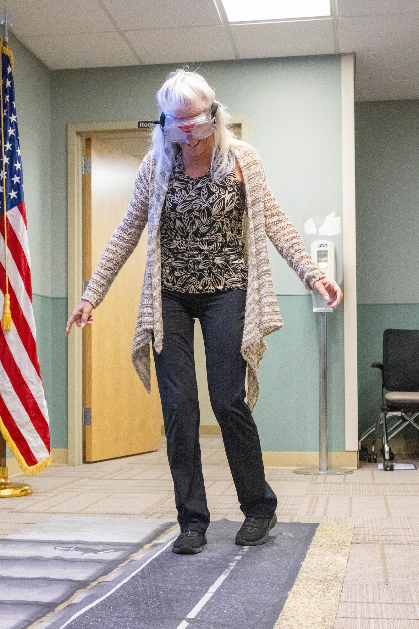 Rosemary Baughman, 736th Aircraft Maintenance Squadron honorary commander, attempts to walk a straight line while wearing drunk goggles during a tour of the medical clinic at Dover Air Force Base, Delaware, July 18, 2024. The HCCs toured various elements of the 436th MDG to familiarize them with the group's facilities, mission and capabilities. (U.S. Air Force photo by Mauricio Campino)