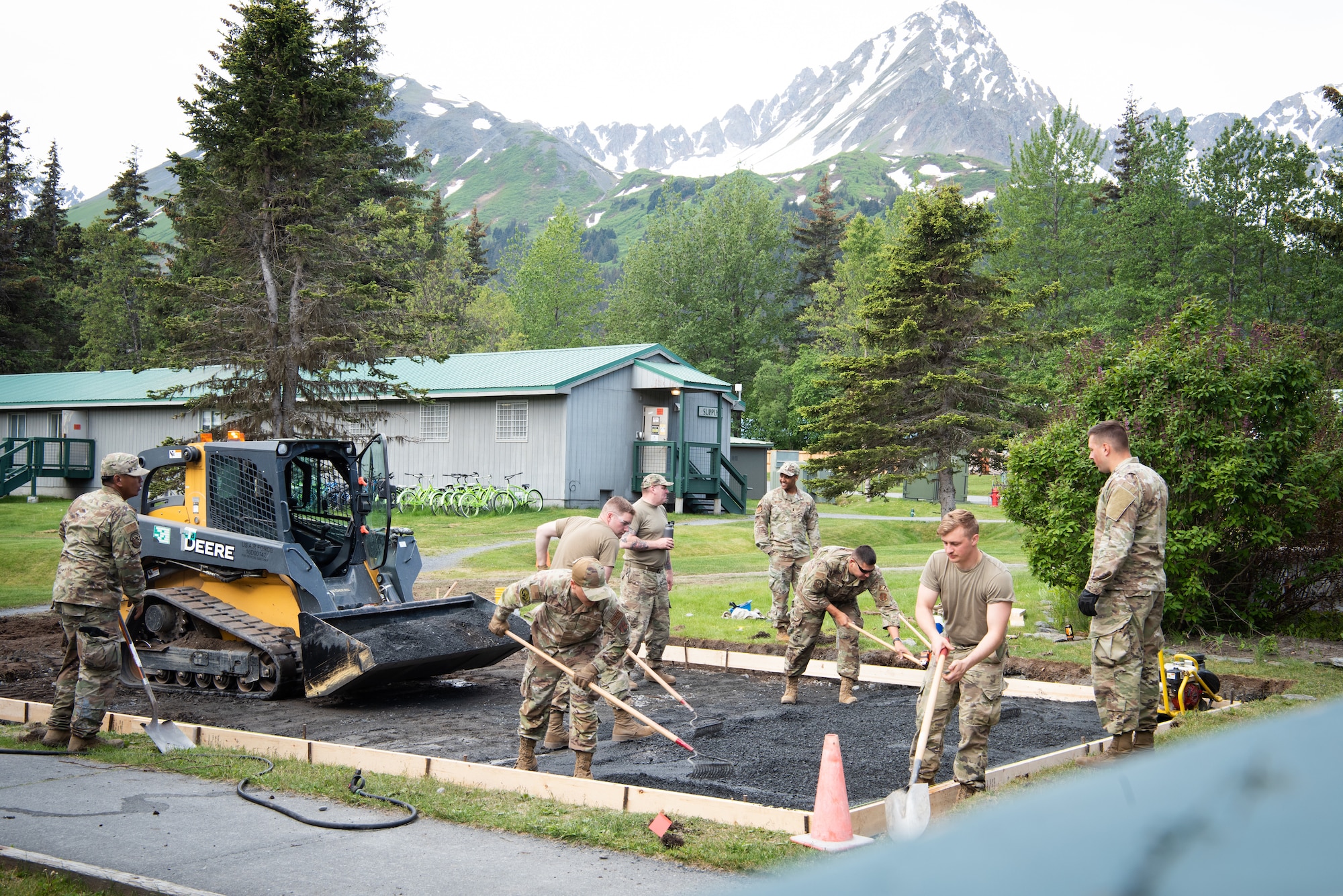 U.S. Air Force Airmen assigned to the 128th Air Refueling Wing Civil Engineer Squadron, Milwaukee, WI, lays the base covert for the concrete pour for a concrete pad at the Seward Military Resort, Seward, Alaska, June 21, 2024. Careful laying of the base covert ensures stability and prevents future deformation of the concrete pad. (U.S. Air National Guard photo by Airman 1st Class Cynthia Yang)