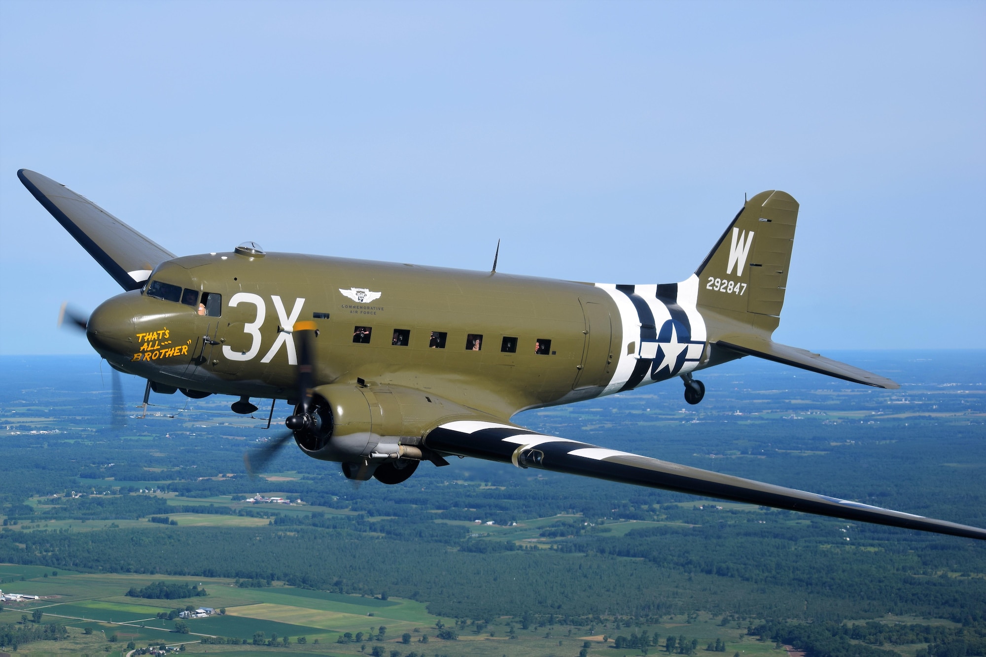 That’s All Brother, a Douglas C-47 Skytrain presented by the Commemorative Air Force (CAF) flies over a green landscape