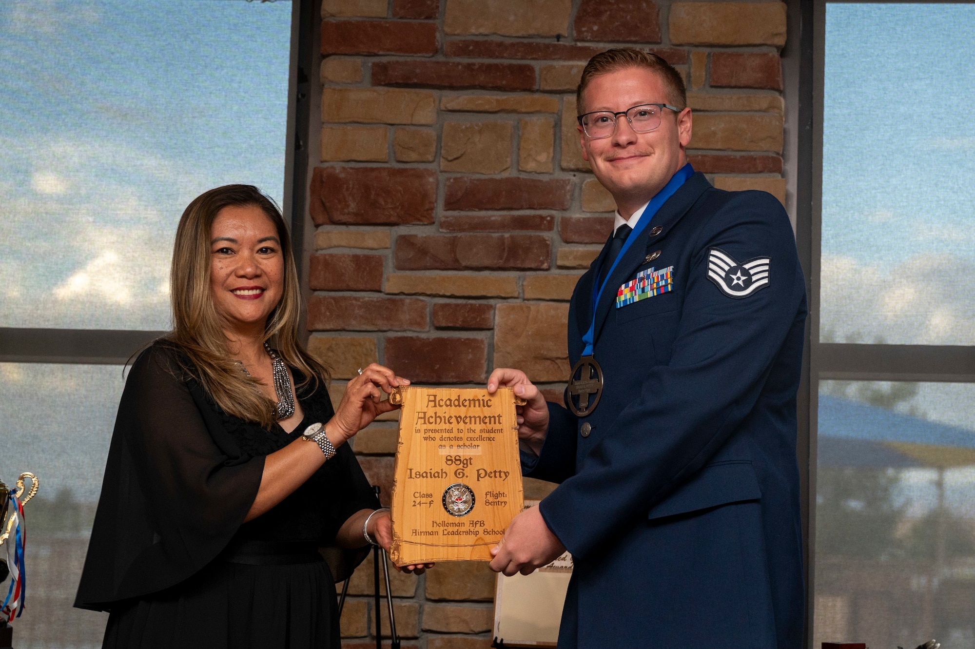 U.S. Air Force Staff Sgt. Isaiah Petty, Airman Leadership School Graduate, right, accepts the Academic Achievement Award from Mrs. Laney Cooper, during the graduation of Joel C. Mayo ALS Class 24-F at Holloman Air Force Base, New Mexico, July 18, 2024.