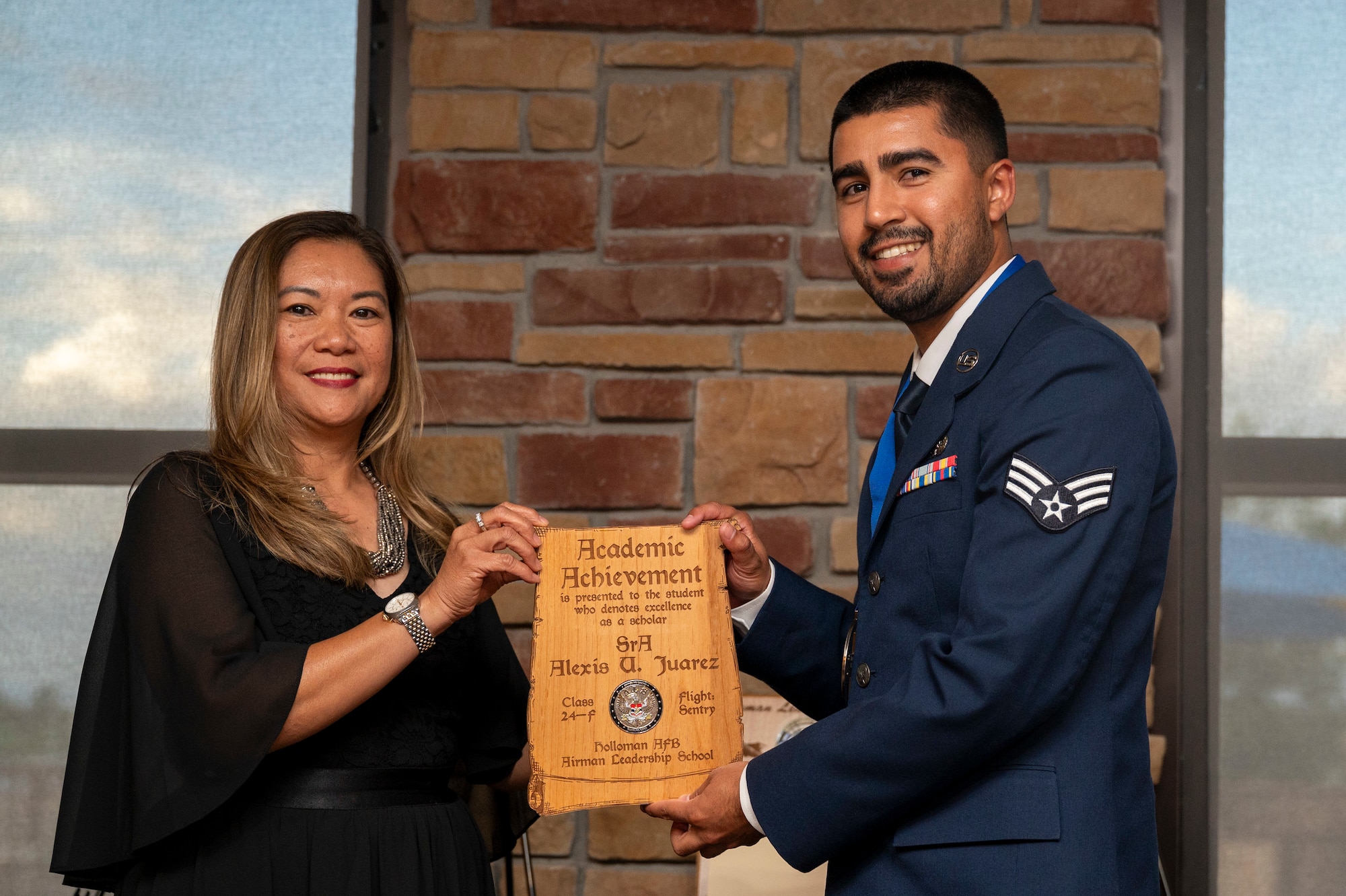 U.S. Air Force Senior Airman Alexis Juarez, Airman Leadership School Graduate, right, accepts the Academic Achievement Award from Mrs. Laney Cooper, during the graduation of Joel C. Mayo ALS Class 24-F at Holloman Air Force Base, New Mexico, July 18, 2024.
