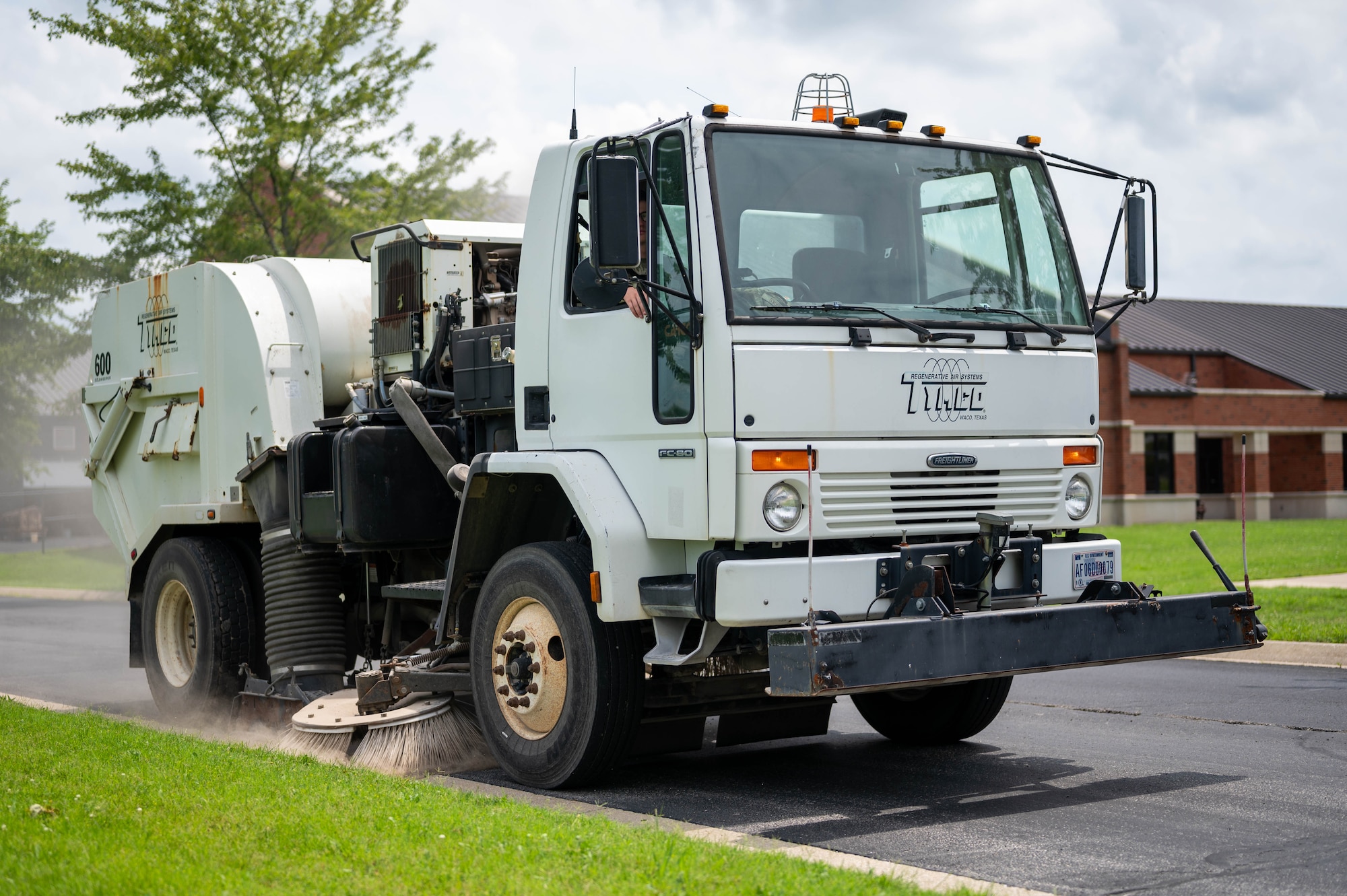 Airman drives a sweeper truck to clean the roads