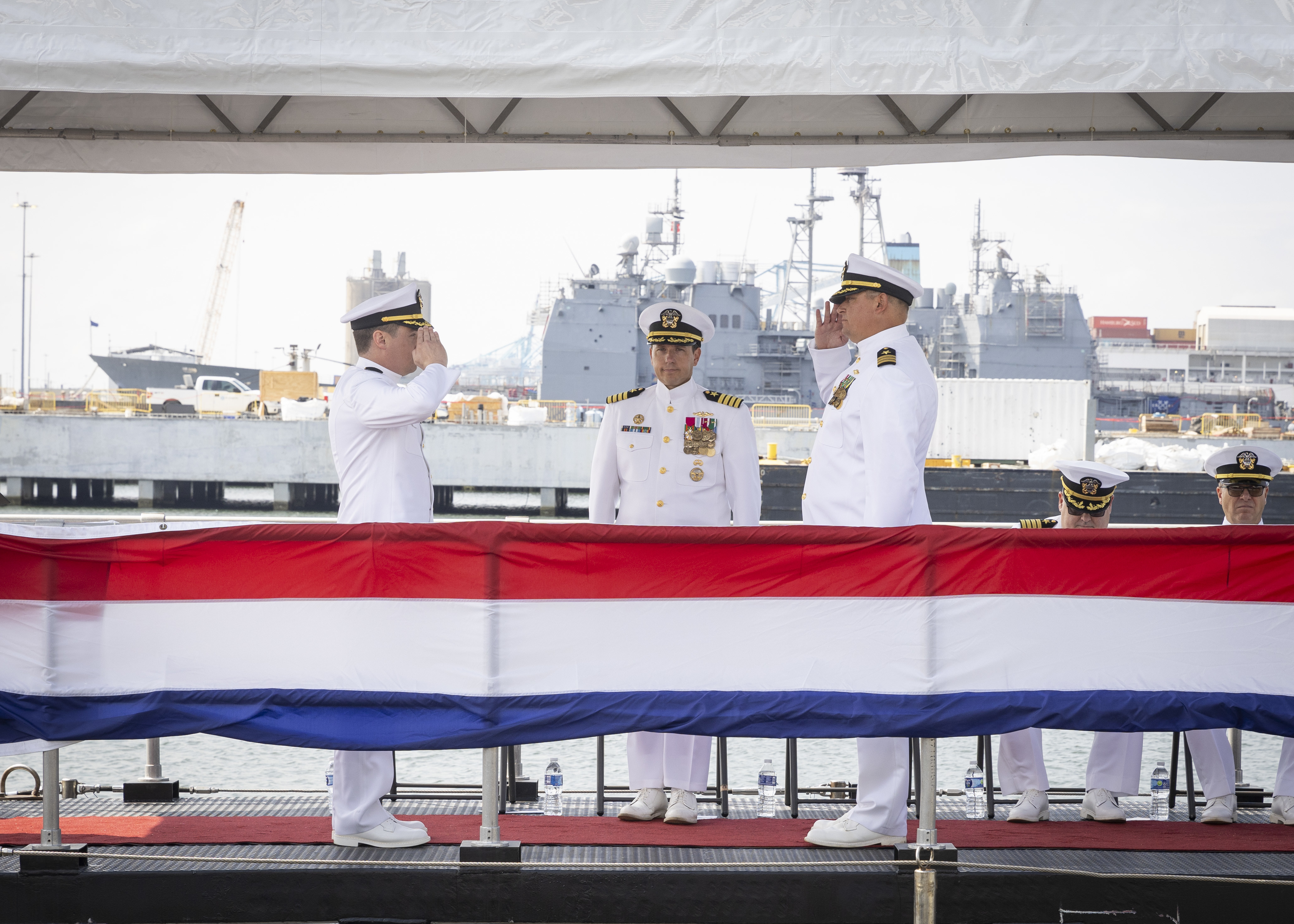 Capt. David Fassel, commodore, Submarine Squadron Six, center, looks on as Cmdr. Keith Turnbull, left, relieves Cmdr. Clinton Christofk, right, as commanding officer of the Virginia-class fast-attack submarine USS Washington (SSN 787) during the boat’s change of command ceremony onboard Naval Station Norfolk, July 19, 2024.