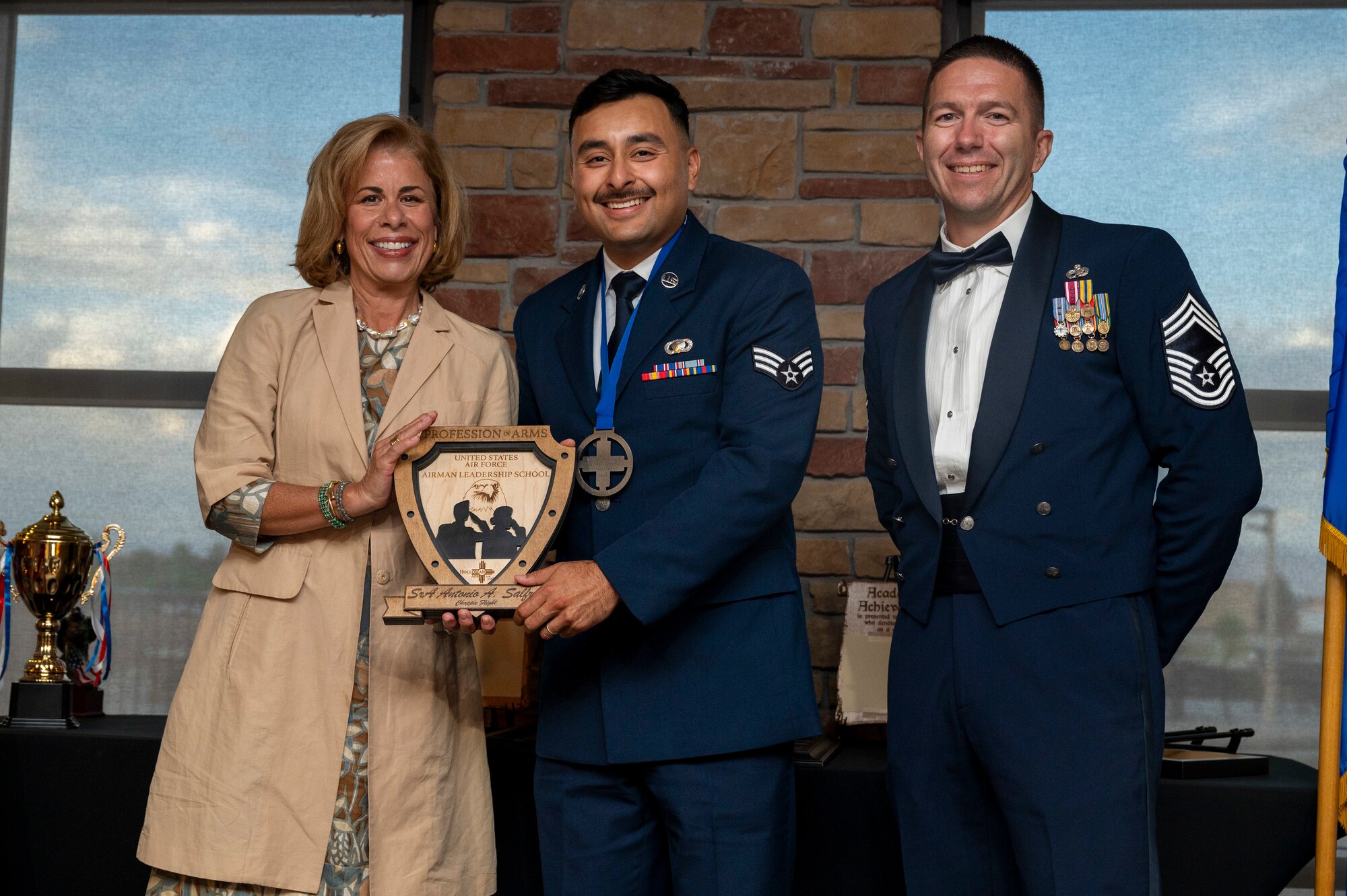 U.S. Air Force Senior Airman Antonio Salfran, Airman Leadership School Graduate, center, accepts the Profession of Arms Award from Ms. Danielle Rondelez, left, and U.S. Air Force Chief Master Sgt. Keith Farmer, during the graduation of Joel C. Mayo ALS Class 24-F at Holloman Air Force Base, New Mexico, July 18, 2024.