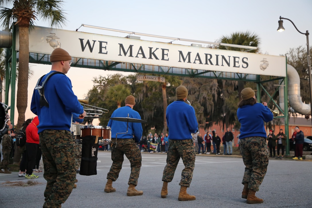 The "Dirty Boots" Brass Band plays in a motivational run at Parris Island under the We Make Marines sign.