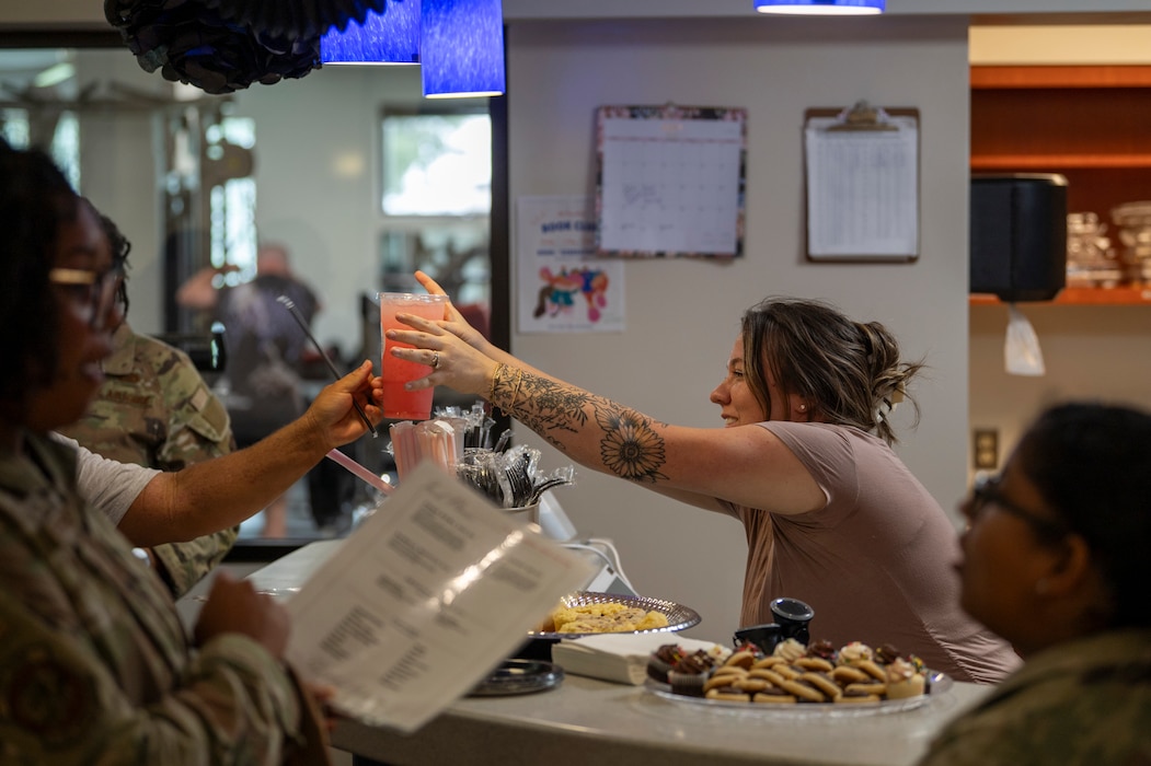 A “Nest Nutrition” employee passes a drink to a customer at Moody Air Force Base, Georgia, July 16, 2024. Nutritional fitness contributes to resilience by helping service members maintain a healthy weight, protecting them against diet-related diseases that affect physical and cognitive functions, and reducing their vulnerability to stress and depression (U.S. Air Force photo by Airman 1st Class Leonid Soubbotine)