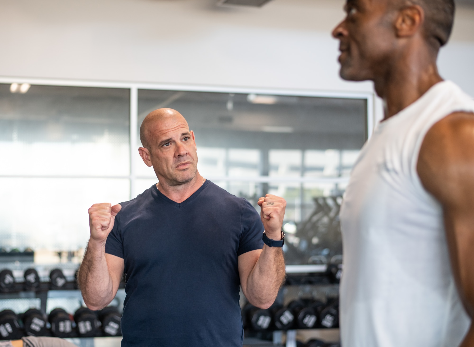 John Hofman, SSC’s certified strength and conditioning specialist, discusses the proper form for a standing barbell overhead press with Tyrone Roach, engineering specialist at the Aerospace Corporation, at the Los Angeles Air Force Base Fitness Center. Photo by Van D. Ha