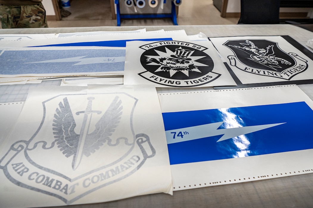 Decals from the 74th Fighter Squadron, 23rd Wing, and Air Combat Command rest on a table at Moody Air Force Base, Georgia, July 16, 2024. Nose art, tail flashes and other identifying signs were added to the A-10C Thunderbolt II after it received its new paintjob from the maintenance depot. (U.S. Air Force photo by Airman 1st Class Leonid Soubbotine)