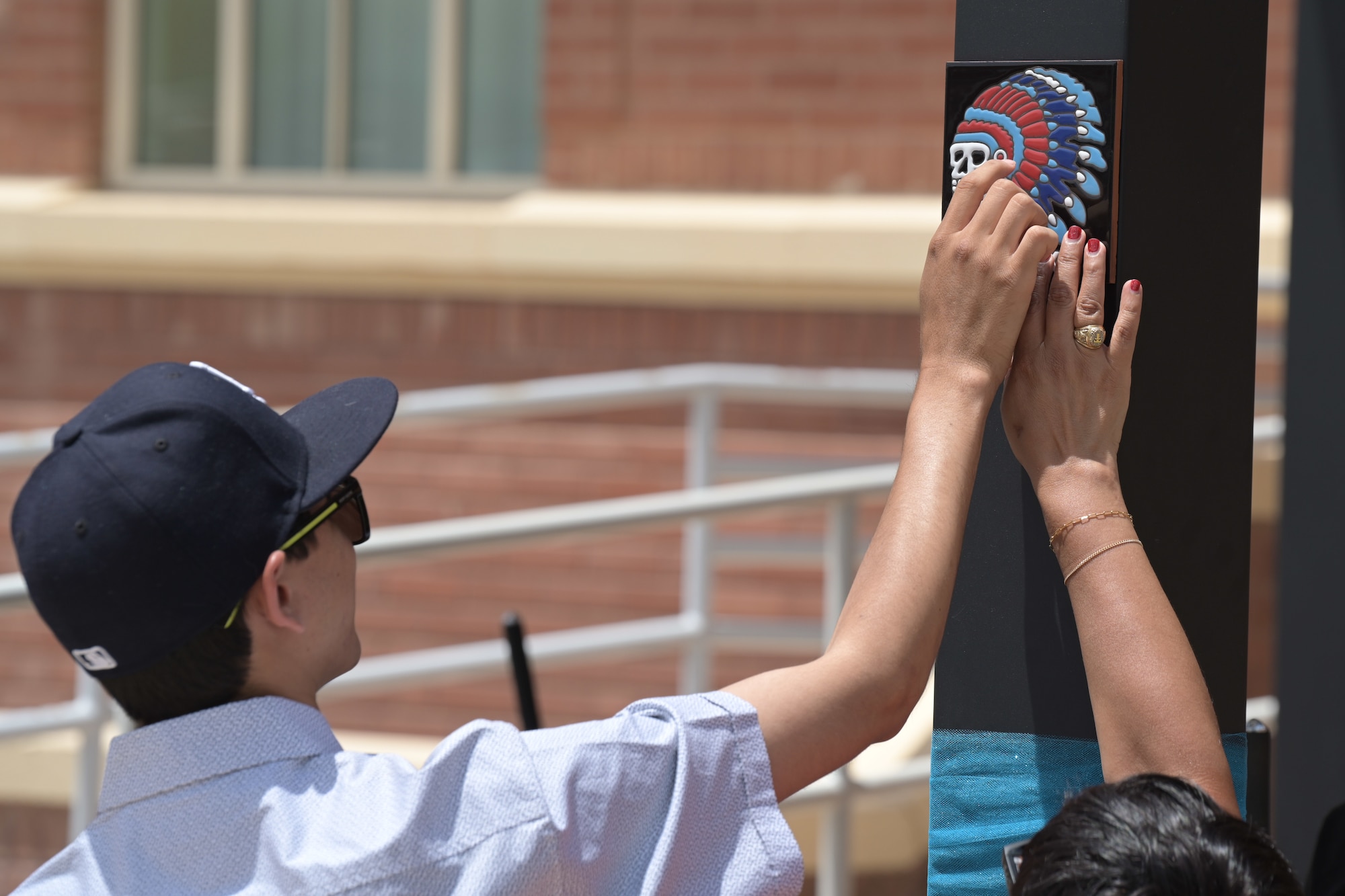 Angel Sanchez, left, feels a tactile symbol of the 29th Attack Squadron at a multi-sensory garden in the New Mexico School for the Blind and Visually Impaired in Alamogordo, New Mexico, July 18, 2024.